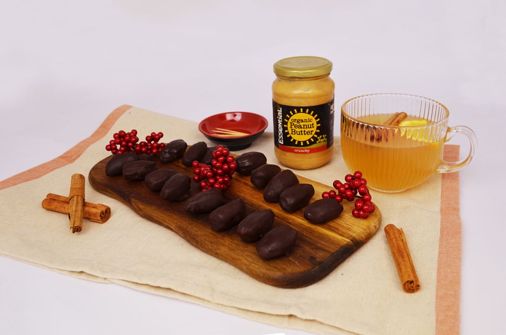 chocolate dates on a wooden board surrounded by winter berries and cinnamon