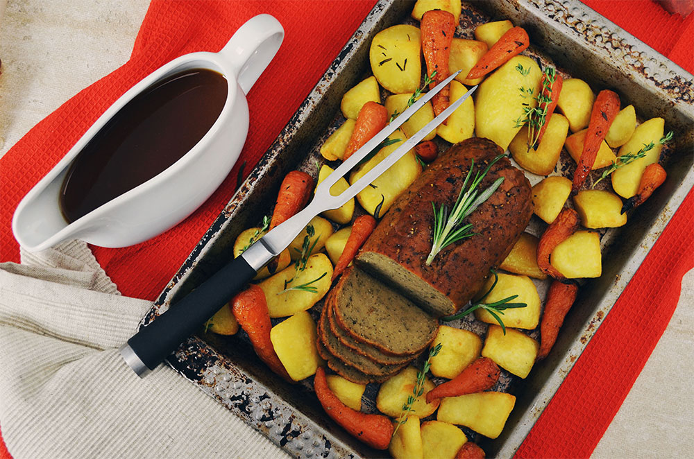 Vegan Turkey-Style joint in a roasting tin with potatoes and carrots