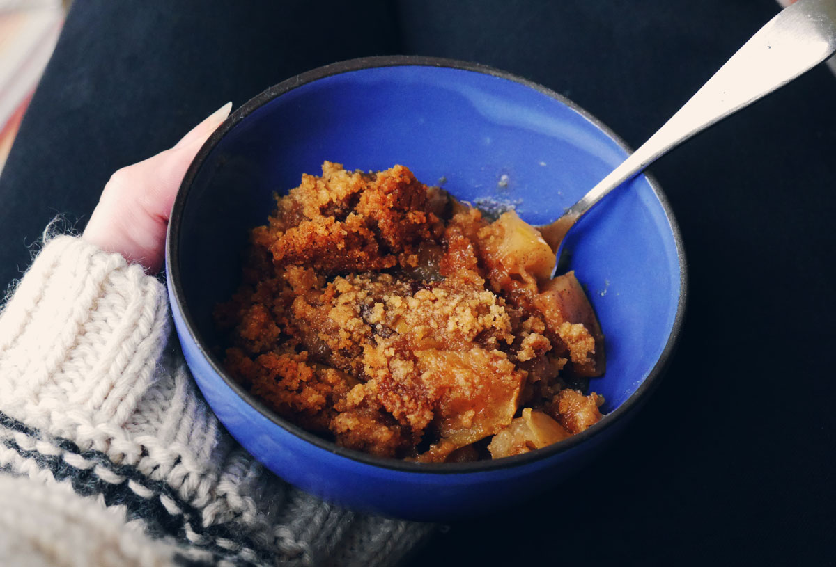 apple crumble in a blue bowl with a spoon