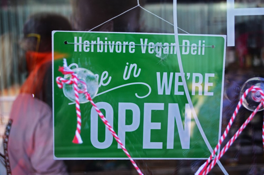 Herbivore Vgean Deli we're open sign in door