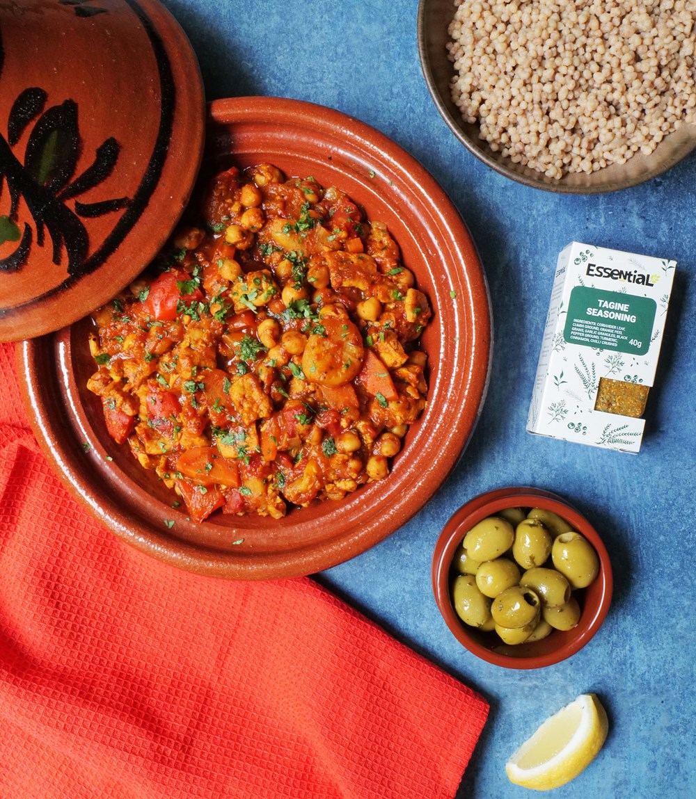 vegan tagine served ina tagine pot with a side of giant cous cous, olives and a lemon wedge